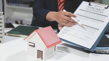 A real estate agent holding a contract agreement with a house model video