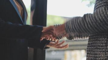 Two people shaking hands in front of a window video