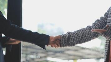 Two people shaking hands in front of a window video