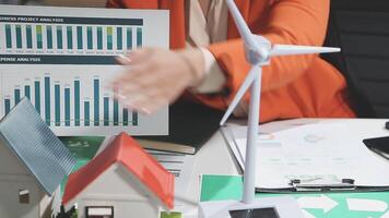 A woman is holding a paper with graphs and a wind turbine on it video
