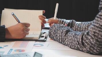 Two people are sitting at a table with a notebook and pen video