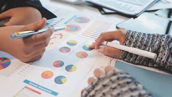 Two people are working on a document with graphs and charts video