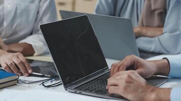 A group of people sitting around a table with laptops video