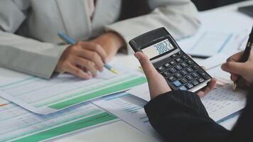 Two people are using a calculator to calculate the numbers video