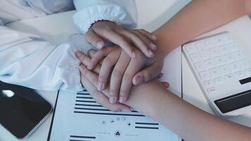 Two people holding hands over a desk with a calculator video
