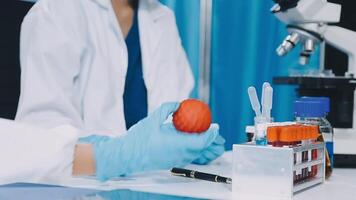 A person in a lab coat is holding an orange video