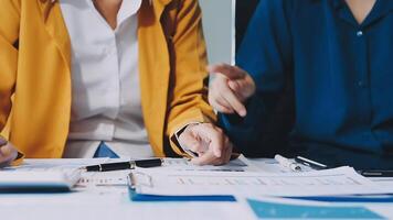 Two business people are sitting at a table with papers and pens video