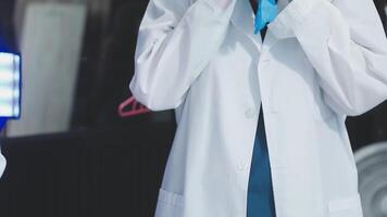 A man in a lab coat is holding a blue light video