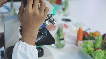 A person in a lab coat looking at a microscope video