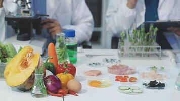 Two people in lab coats are working on a table with food video