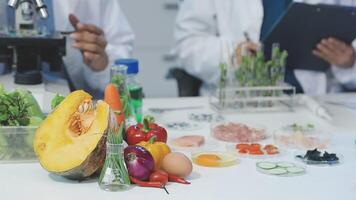 Two people in lab coats are working on a table with vegetables and fruit video