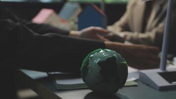 A green globe sitting on a table with two people video