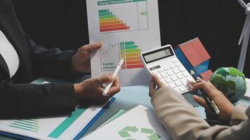 Two people are holding a calculator and paper with an energy chart video