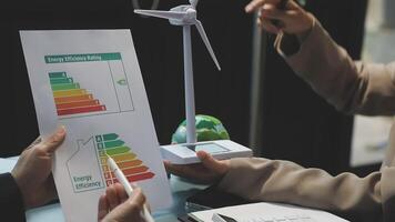 Two people are holding a paper with a wind turbine on it video