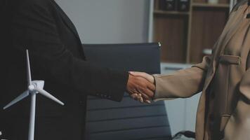 Two business people shaking hands in front of a wind turbine video