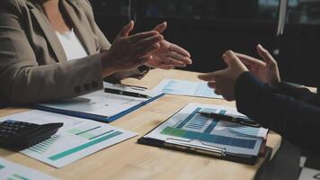 Two business people talking at a table with papers and calculators video