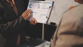 A business person is holding a clipboard and looking at a chart video