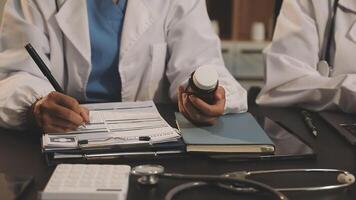 Two doctors are sitting at a table with a laptop and papers video