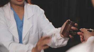A woman in a lab coat is handing a small object to another person video