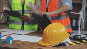 Two people in hard hats and vests standing next to a table with construction equipment video