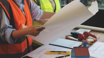 Two people in safety vests holding papers and building plans video