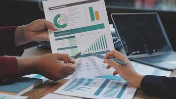 Two people are looking at a document with graphs on it video