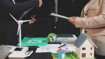 Businessman and woman working on a project with wind turbines video
