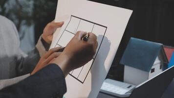 A person is drawing on a piece of paper with a house on it video