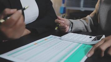 Two business people are working on a document with a calculator video