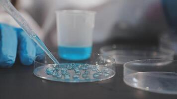 A person in a lab coat is holding a tube with blue liquid video