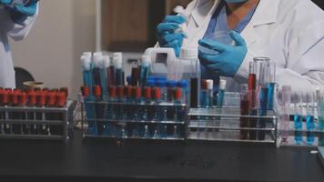 Two people in lab coats and gloves working on a test tube video