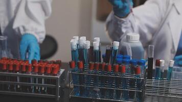 Two people in lab coats are working on a table with test tubes video