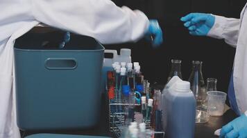 Two people in lab coats and gloves working on a table video