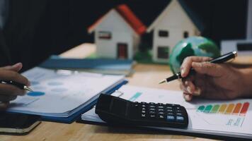 Businessman's hands writing on paper with calculator and house model video