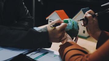 Two people are holding a pen and a paper with a house on it video