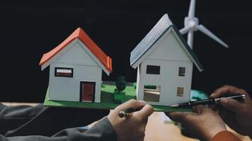 Two people holding a model of a house with wind turbines video