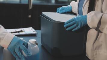 Two people in lab coats are holding a container video