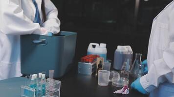 Two people in lab coats are working on a table video