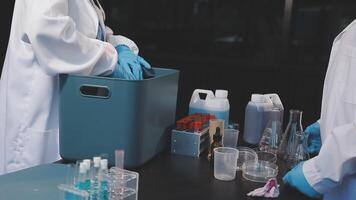 Two people in lab coats and gloves are working on a table video