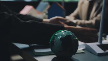 A green globe sitting on a table with two people video