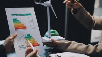 A man and woman are holding a paper with a wind turbine on it video