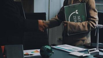 Two people shaking hands over a desk with a green folder video