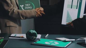 Two people shaking hands over a table with a green recycling bin video