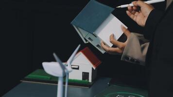A man is holding a paper with a house and wind turbines video