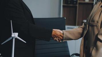 Two business people shaking hands in front of a wind turbine video