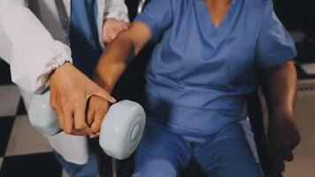 A nurse is holding a dumbbell in front of a woman in a wheelchair video