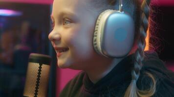 Close up happy Caucasian smiling excited little girl gamer good streaming talking to microphone talk radio mic daughter kid child teen playing computer virtual game cyber addiction at home chat video