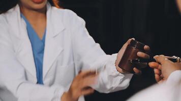 A woman in a lab coat is handing a small object to another person video