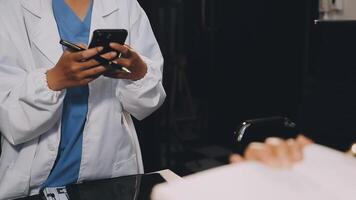 A doctor is using her phone while looking at a patient video