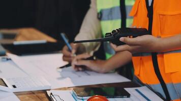 A man in an orange vest and safety vest is working on a computer video